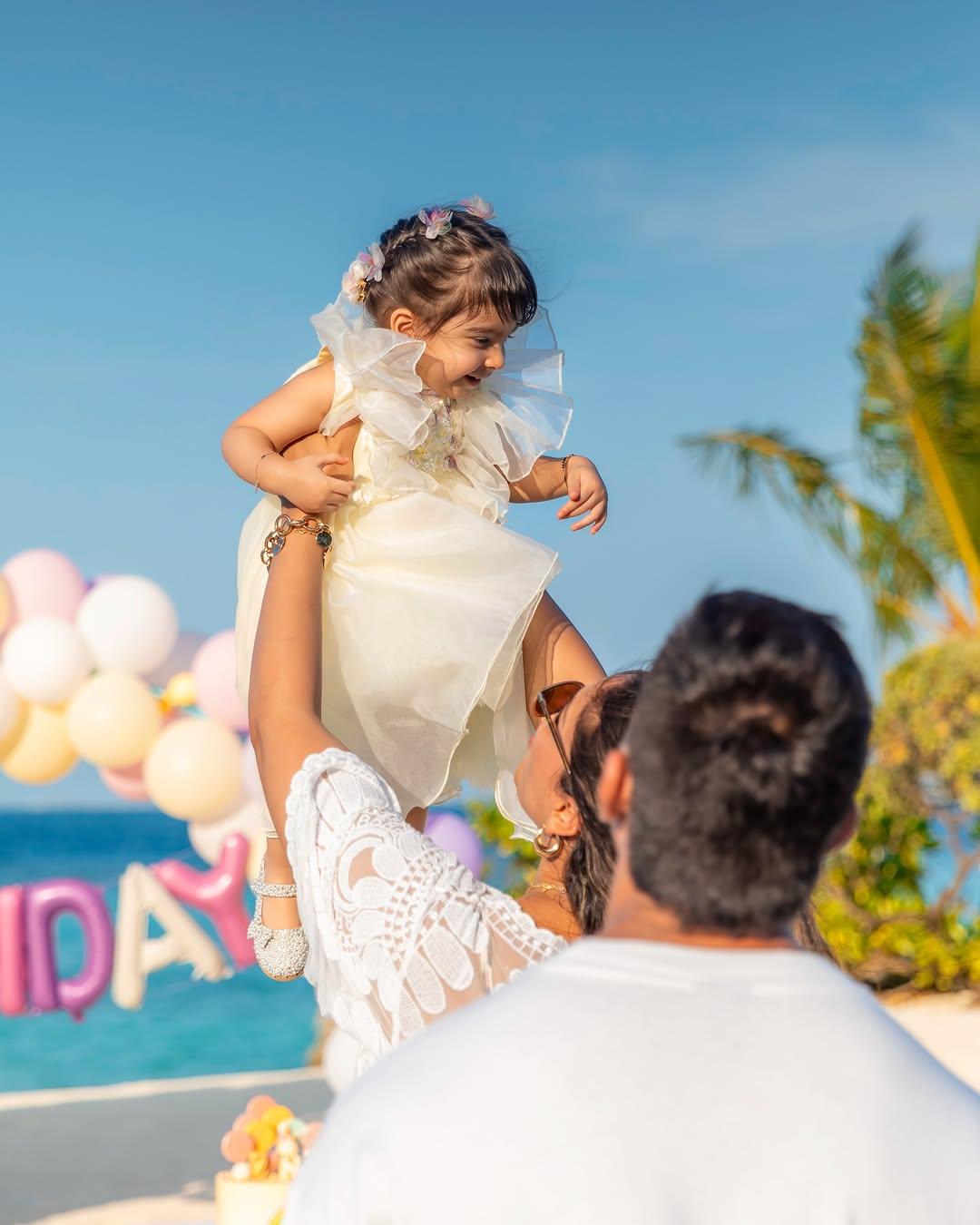 This picture has Bipasha holding Devi in her hands while Karan watches and adores them from behind
