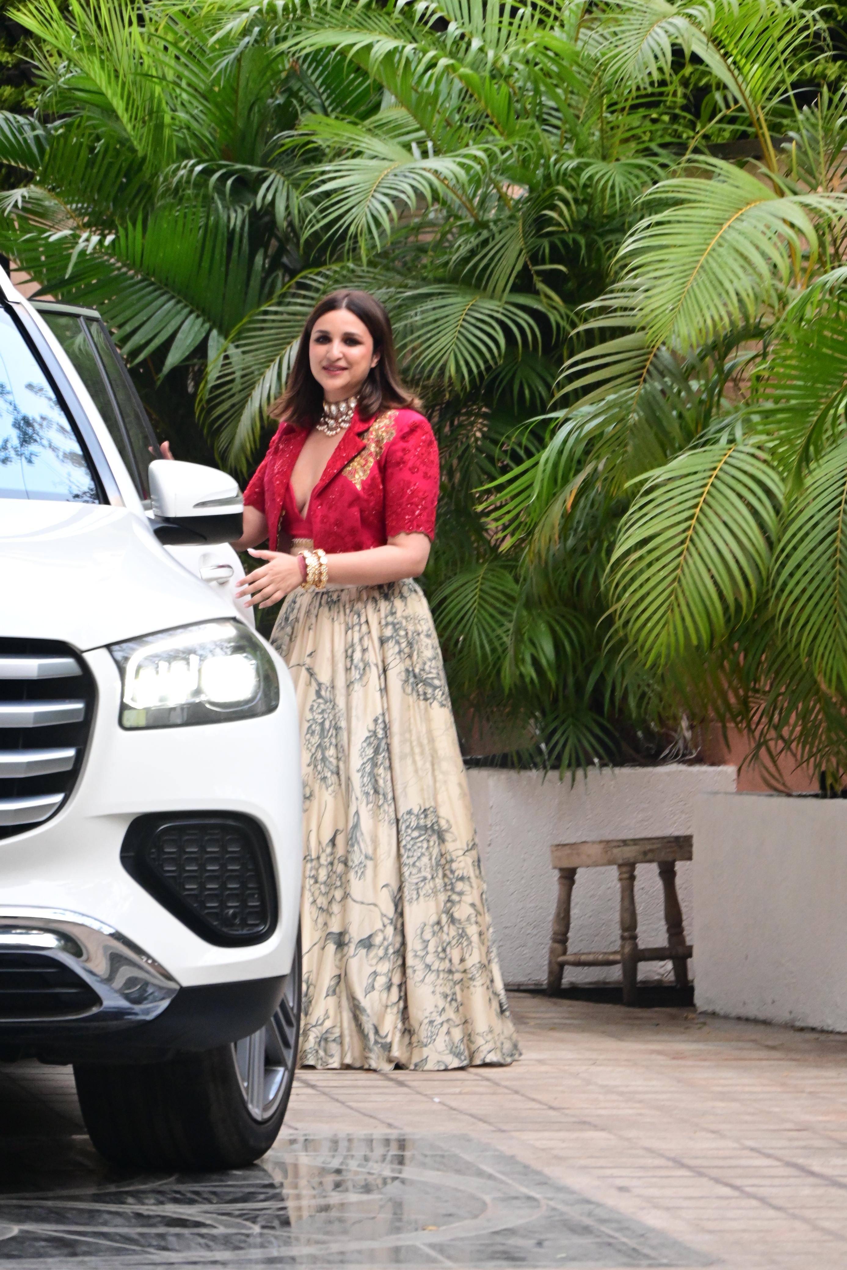 Parineeti was seen wearing a white long skirt featuring black prints. The actress paired the skirt with a red deep-neck blouse and a matching jacket with golden embroidery. She paired the outfit with a stylish, intricate choker and multiple bangles.