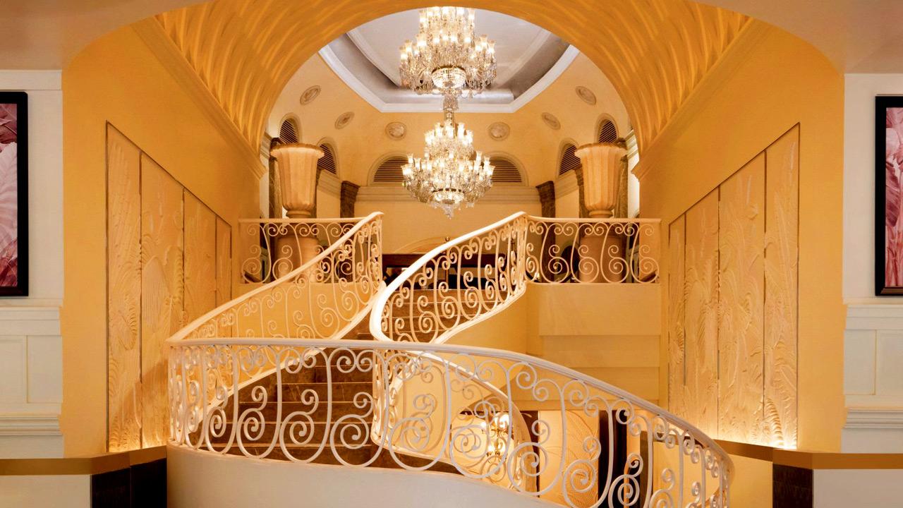 A winding staircase and chandelier paired with modern seating add to the decor