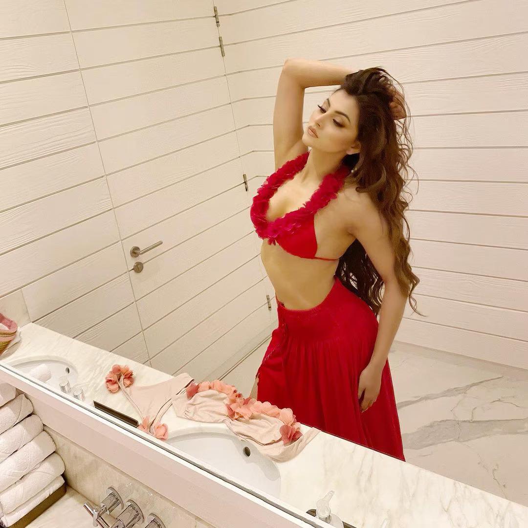 Urvashi Rautela stunned in a red bralette paired with a beautiful long blood-red skirt featuring a thigh-high slit
