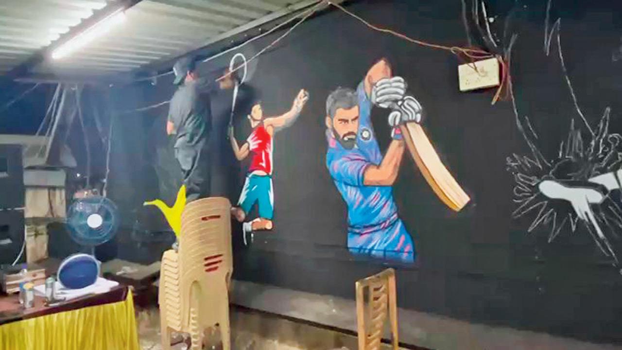Rahul Maurya works on the graffiti mural of cricketer Virat Kohli