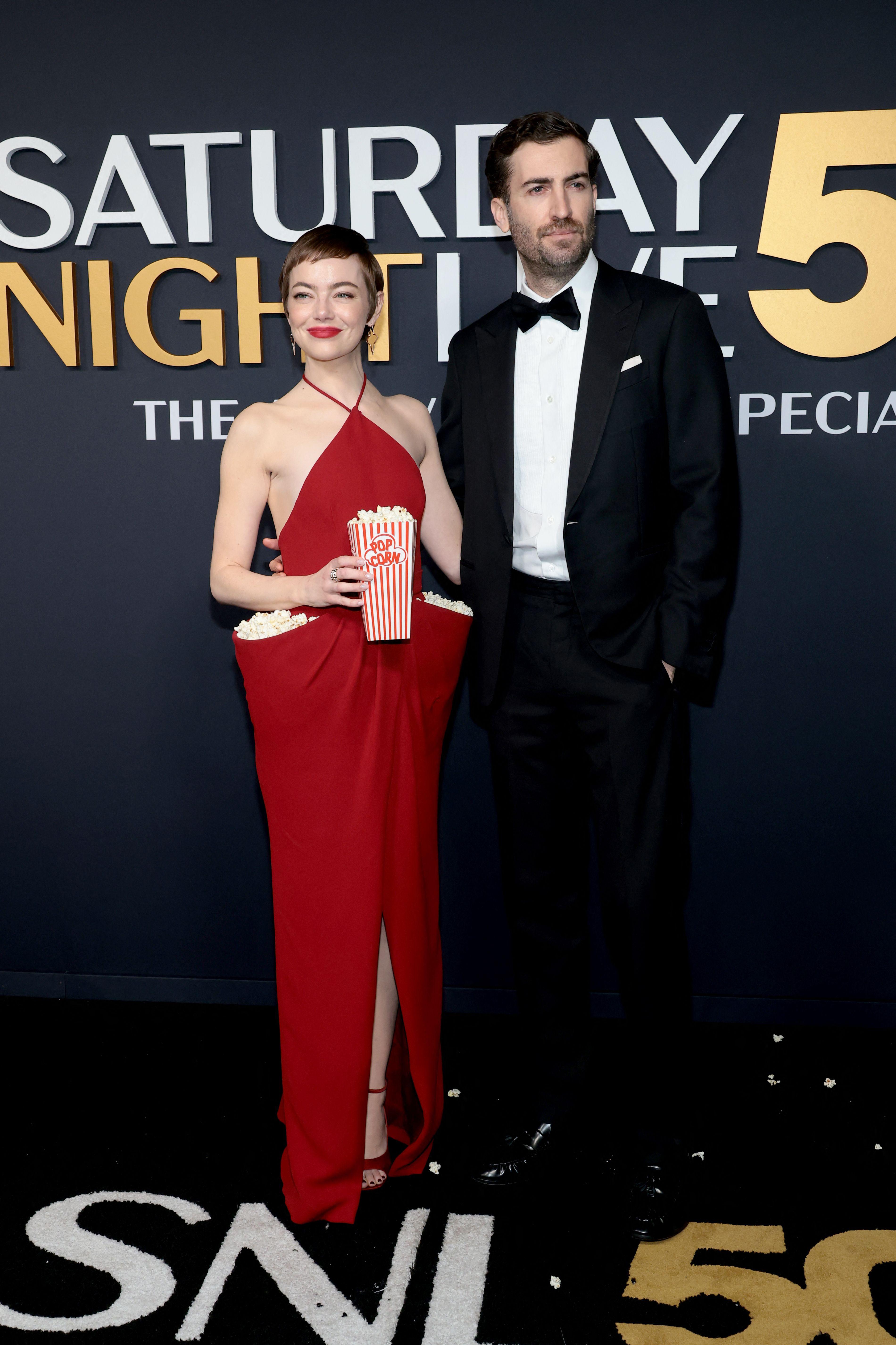 Emma Stone stepped onto the red carpet with partner and former SNL writer Dave McCary sporting a custom Louis Vuitton, cinema seat red, halterneck dress. The dress had two pockets that were filled with popcorn