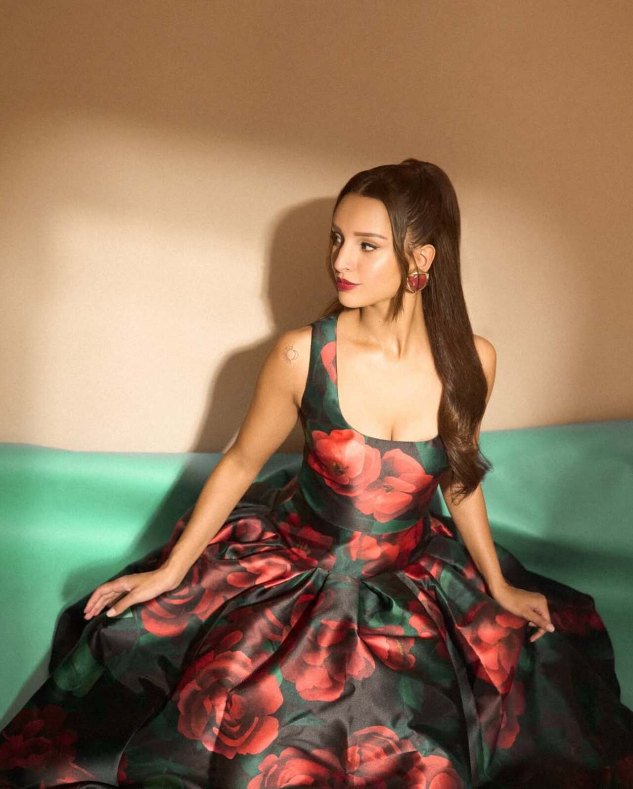 Triptii Dimri channeled her inner retro diva by donning a floral midi gown in the hues of red and phthalo green. She gave her hair a 90s effect with a half-tied look and opted for glamorous makeup with bold red lips.