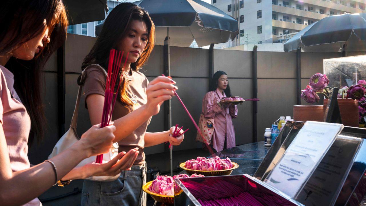 A woman (R) holds pink lotus flowers as others hold incense sticks in front of a statue of the Hindu goddess Lakshmi, revered for bringing love and fortune, in in Thailand's Bangkok on the eve of Valentine's Day