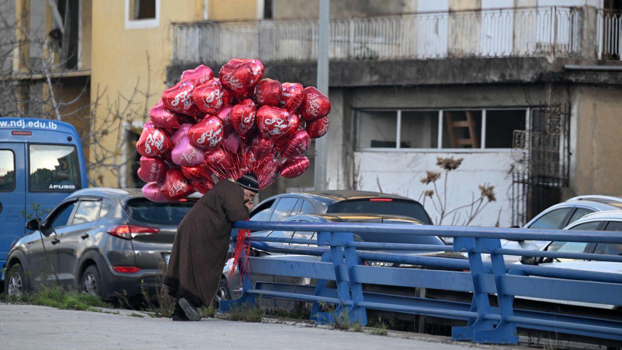 An ambulant vendor carries heart-shaped balloons for sale on February 13, 2025, on the eve of Valentine's Day celebrations in Lebanon