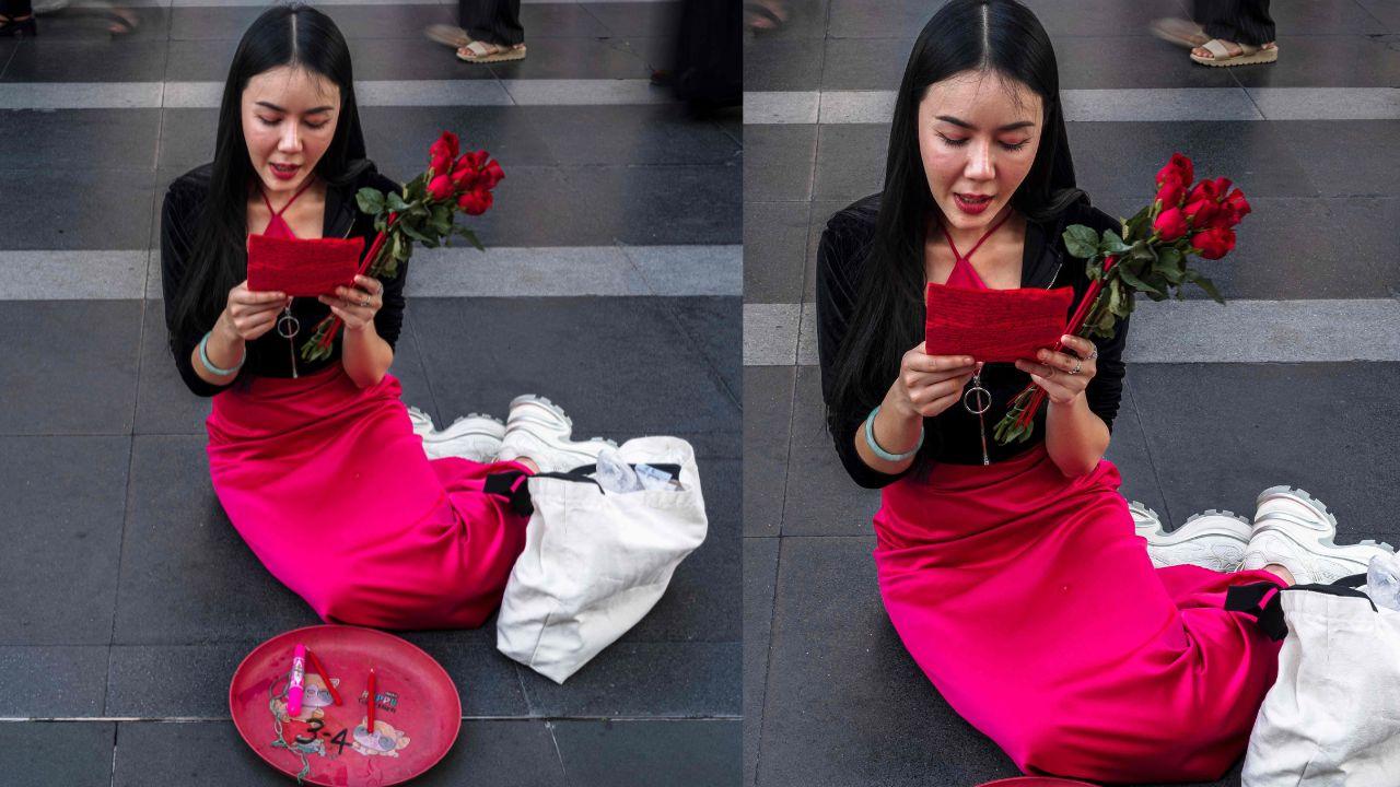 A woman holds a red rose as she prays at the Trimurti Shrine, which is believed to bring love to those who worship before it, in front of the Central World shopping mall in Thailand's Bangkok on the eve of Valentine's Day