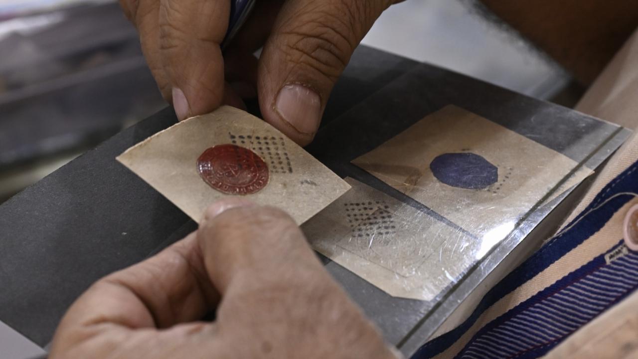 In this picture, a stamp collector can be seen observing a rare stamp at the Nargis Coin Centre stall on opening day of the exhibition.