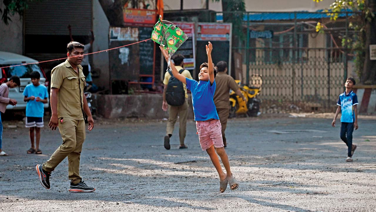 A child helps a kite flier by launching it into the air at Colaba. Pic/Atul Kamble