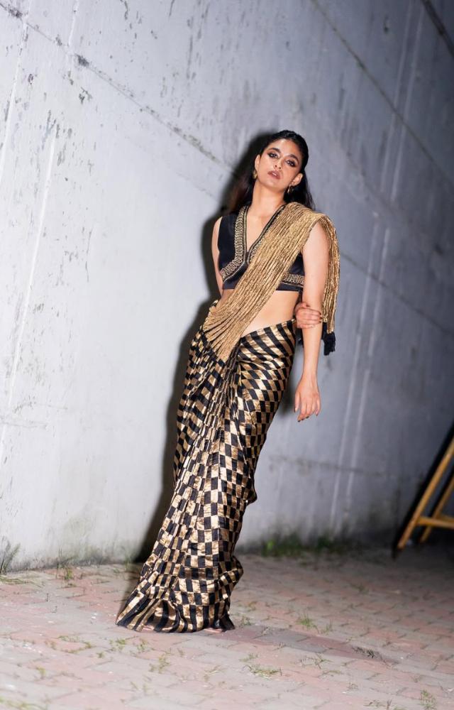 Keerthy looked eye-catching in a black and golden saree with intricate prints on the pleats. Her short pallu and sleek hairdo complemented the ensemble