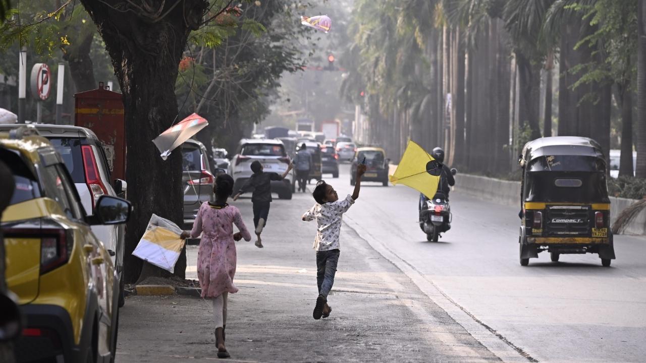 Two kids on their way to fly kites at Vile Parle