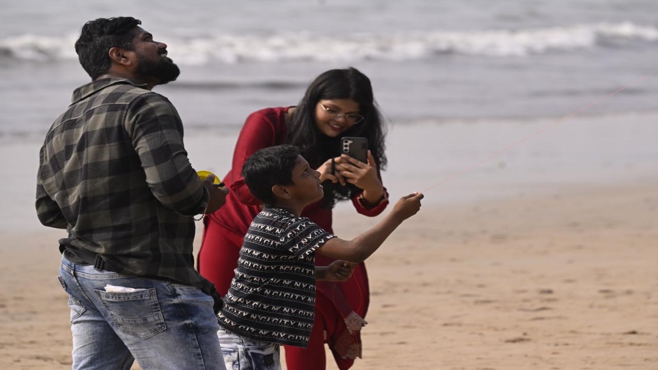 A woman captures a child flying a kite in her camera