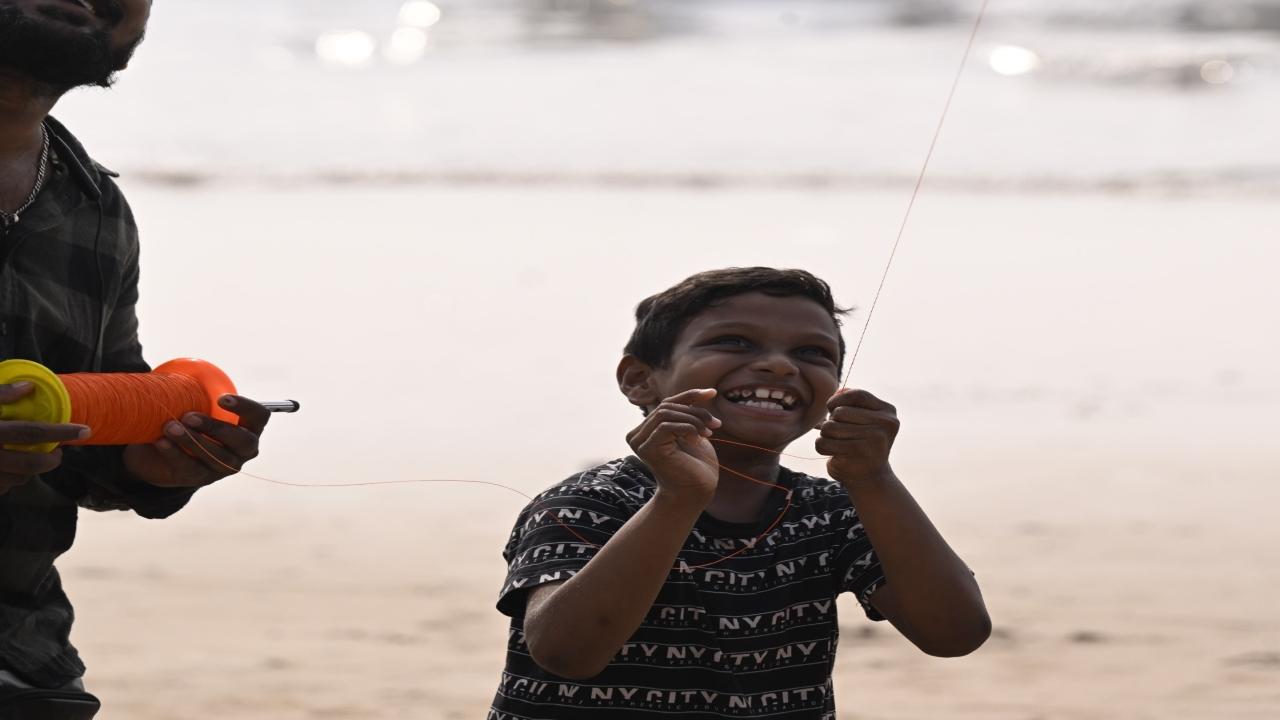 A child watches enthusiastically as his kite soars into the skies