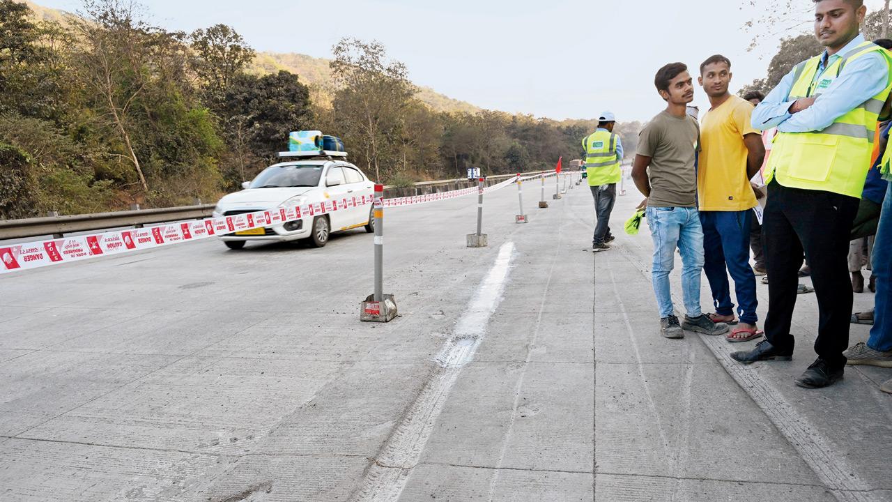 Workers use epoxy to repair tyre marks on the concrete road of NH 48