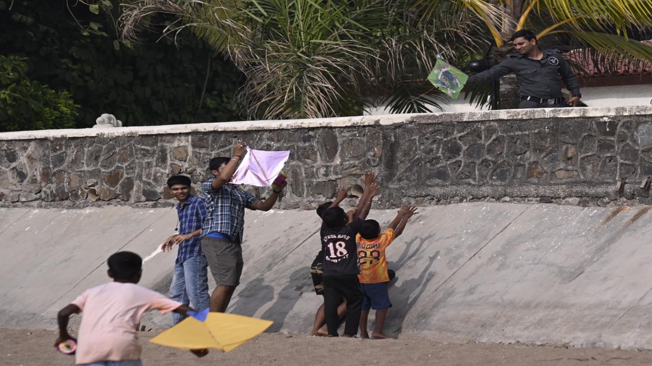 A security guard returns a kite to children after it fell across the fence