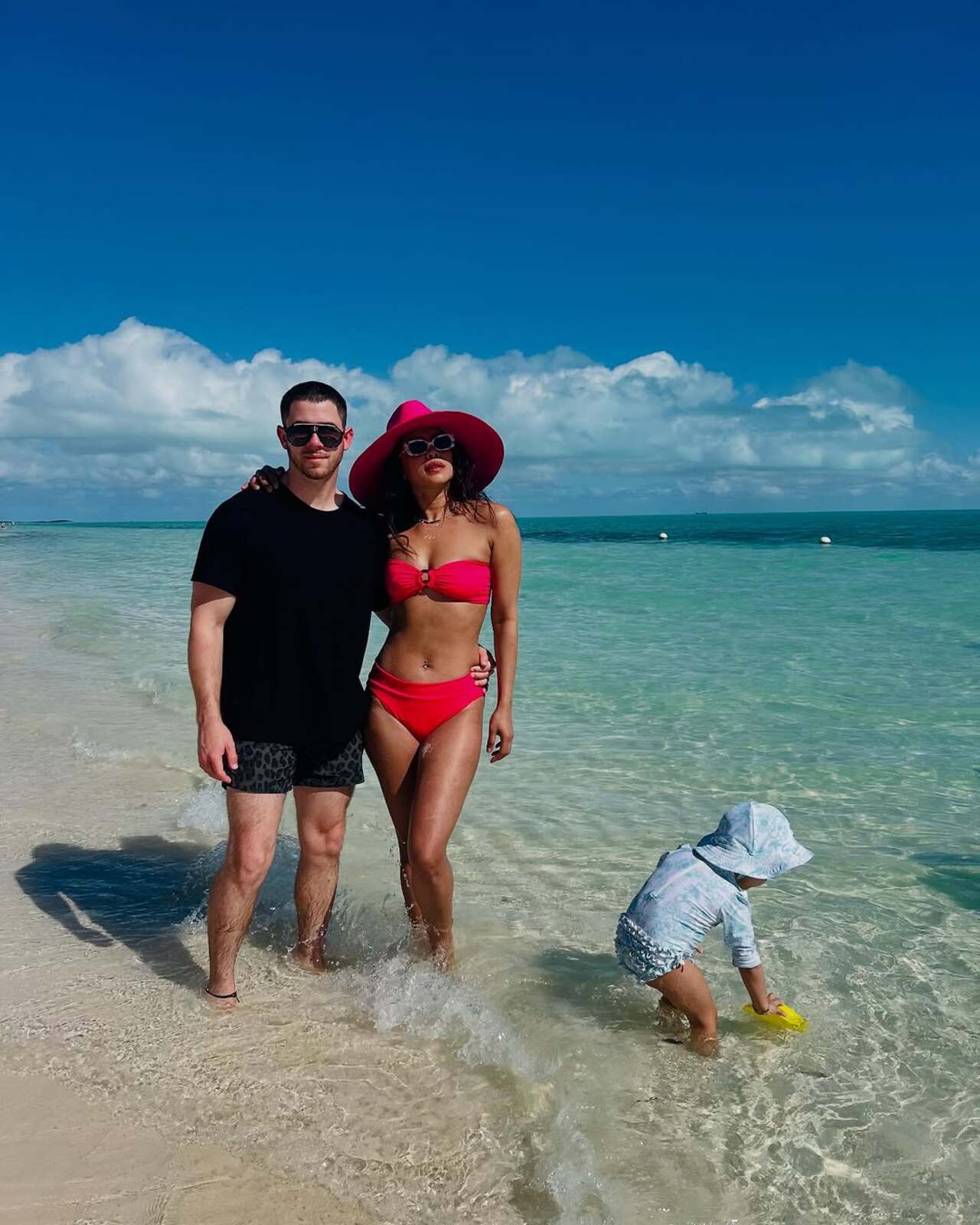 Another image showed her sporting a red bikini posing alongside Nick on the beach while her daughter played with water