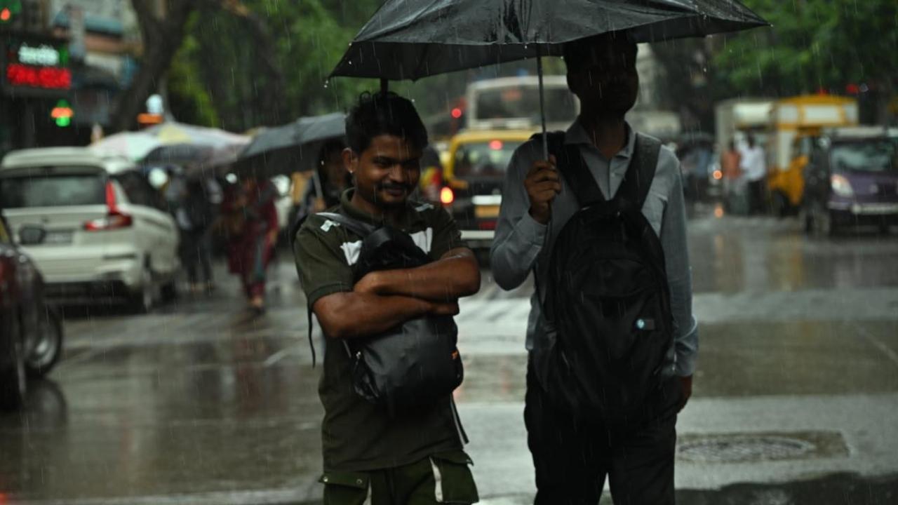 Commuters were seen taking shelter under umbrellas to avoid the sudden downpour
