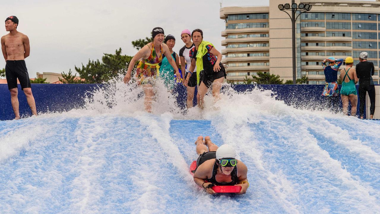 Domestic tourists watch as a man uses a slide into a swimming pool at the Myongsasimni Water Park in the Wonsan Kalma Coastal Tourist Area in Wonsan, North Korea's Kangwon Province on July 2