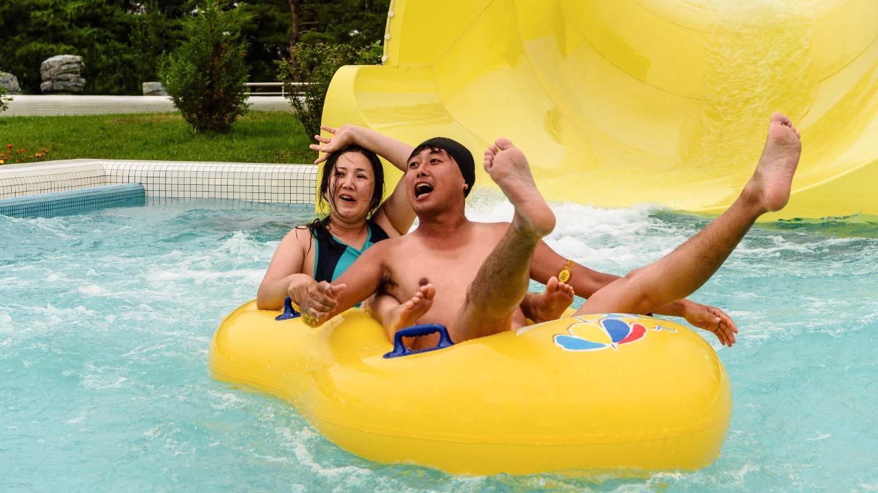 Clearly enjoying themselves, the tourists react after riding a slide into a swimming pool at the Myongsasimni Water Park in the Wonsan Kalma Coastal Tourist Area in Wonsan