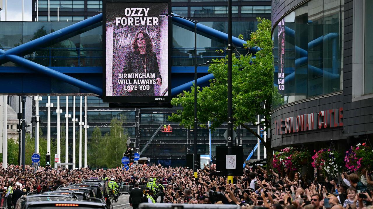 Mourners and music fans line the streets to pay their respects as the funeral cortege of Ozzy Osbourne, the late lead singer of Black Sabbath, makes its way through Birmingham, central England on July 30