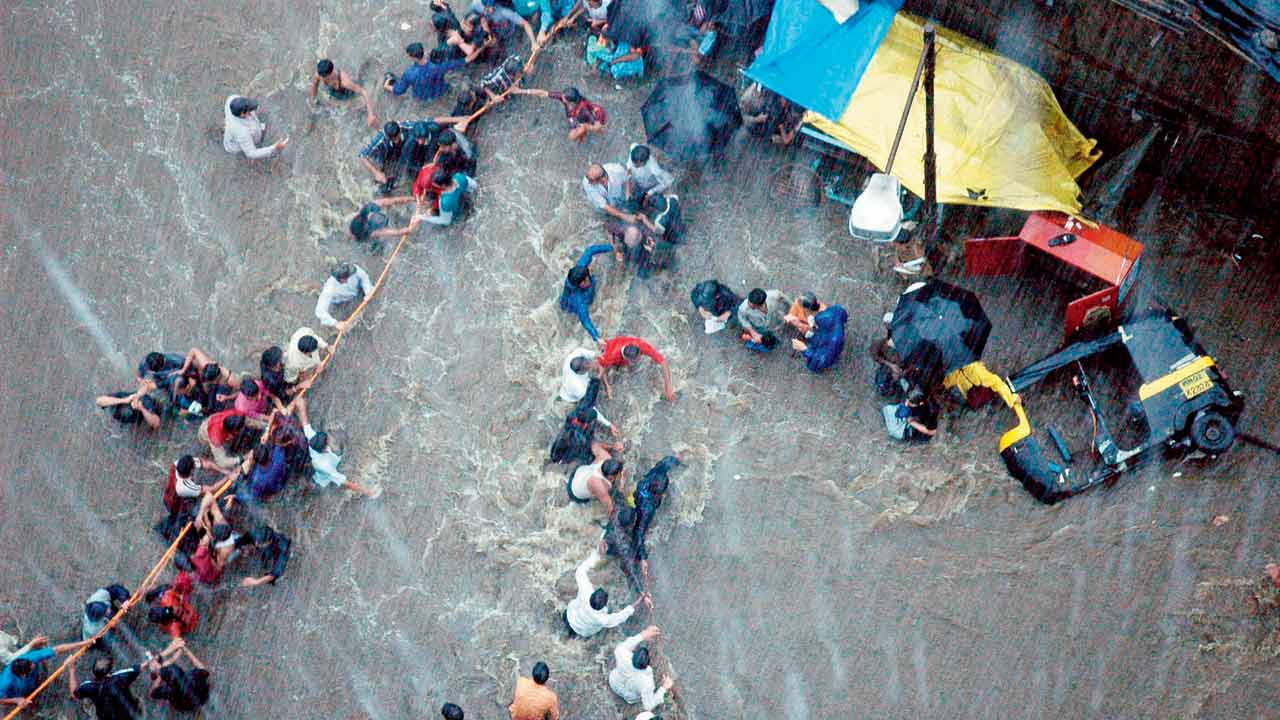 A dated photograph from July 26 shows people forming a human chain by holding each other as they try to make their way through the hip-level waters near Manish Park in Andheri East. Pic/Rane Ashish