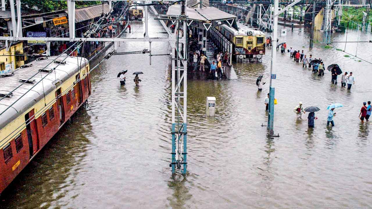 Mumbaikars wade past stranded trains at Mahim. Pic/Ashish Raje; Fotocorp