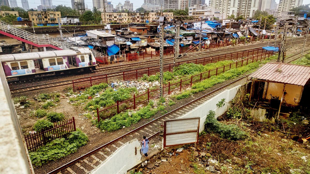 A woman walks through an opening in the wall and gates to illegally cross the railway tracks. Pics/Rajendra B Aklekar