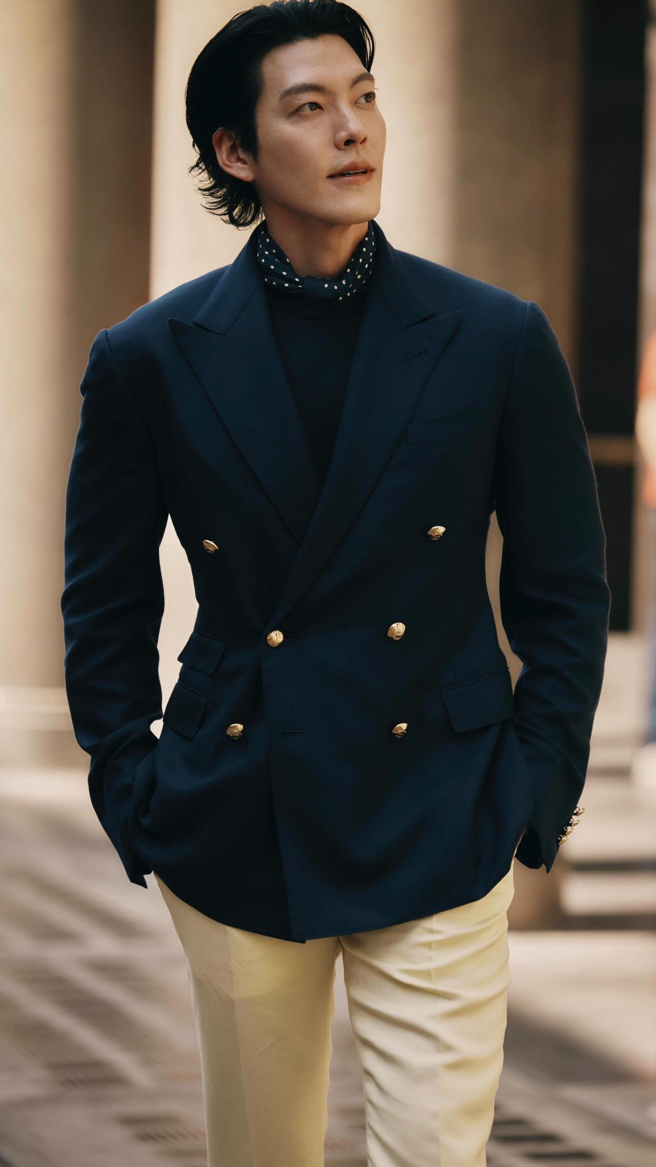 Kim Woo-bin brings sophistication and class in this black structured double-breasted jacket. The accentuated waist creates a perfect symphony with the gold buttons. He pairs it with cream pants, creating a beautiful colour scheme.