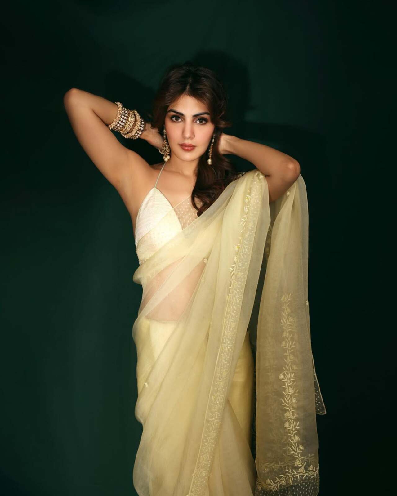 Channelling old-world grace, this ivory-yellow drape feels whisper-light. The barely-there blouse, gajra hair, and stacked bangles evoke timeless nostalgia—like a Satyajit Ray heroine reimagined with Gen Z softness