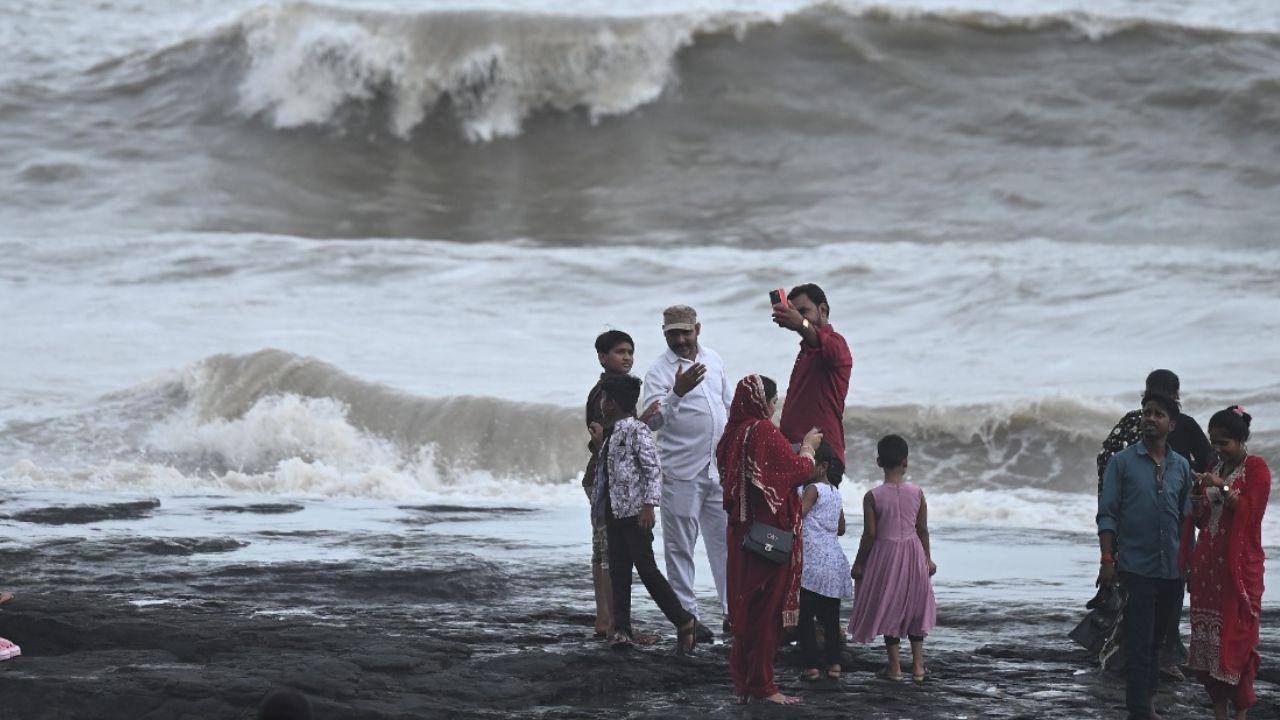 A couple silently watches the swelling sea, as waves slam against the rocks on Saturday afternnon amid high tides at Band Stand
