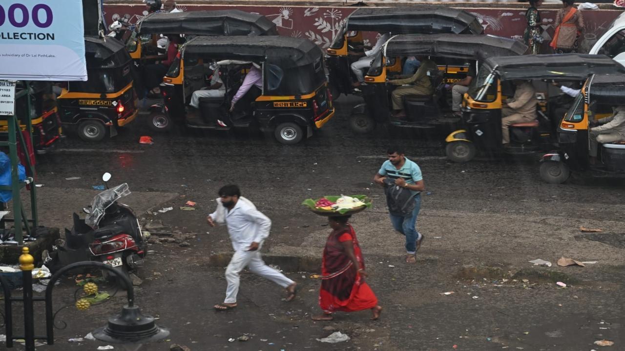 A woman balances a basket on her head while walking through puddles outside Borivali station. PIC/SATEJ SHINDE
