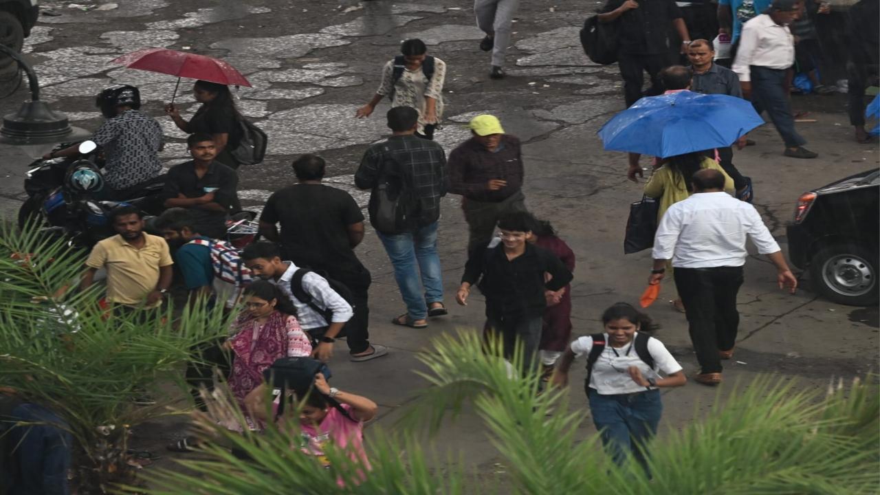 People make their way across pothole-ridden streets outside the station: some with umbrellas, others without any rain gear