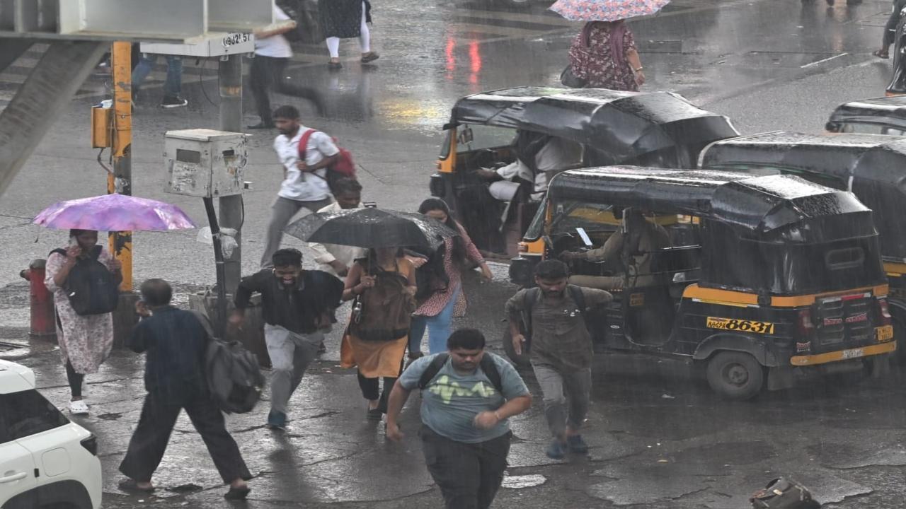 Commuters rush to reach the station after stepping out of rickshaws at Borivali station as rain intensifies