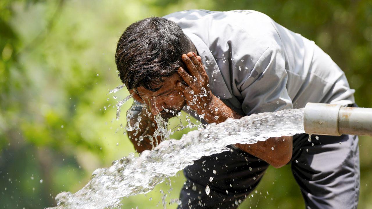 A man splashes water on his face to cool off amid intense heat