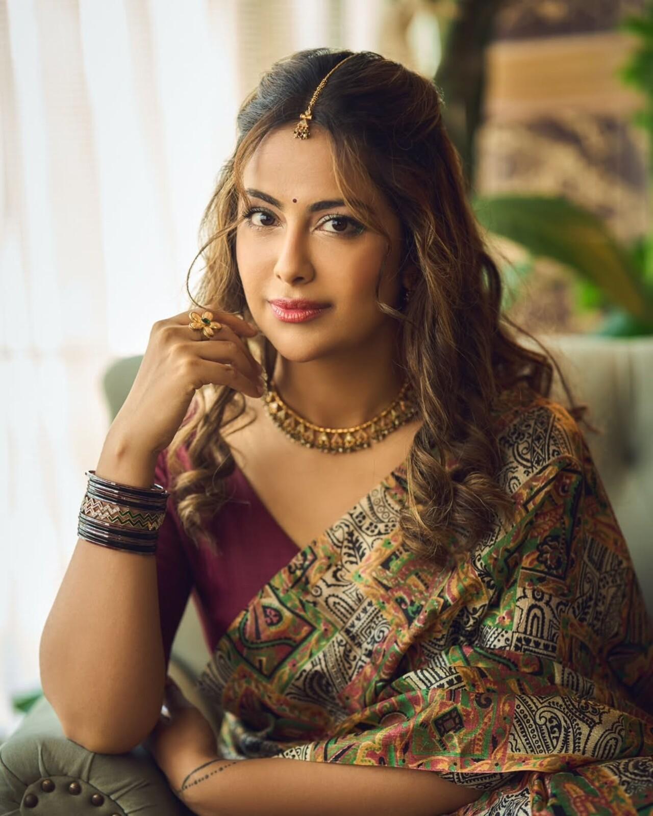 Avika stunned in a multicoloured tribal-print saree paired with a deep maroon blouse. Gold temple jewellery, stacked bangles, and that soft curled hairstyle bring in rich, nostalgic Indian charm