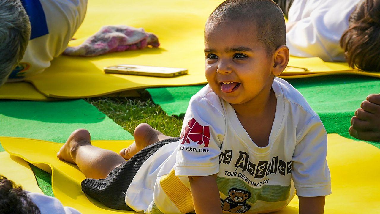 A toddler joins a yoga session held on International Yoga Day at the lawns of Kartavya Path in New Delhi on Saturday