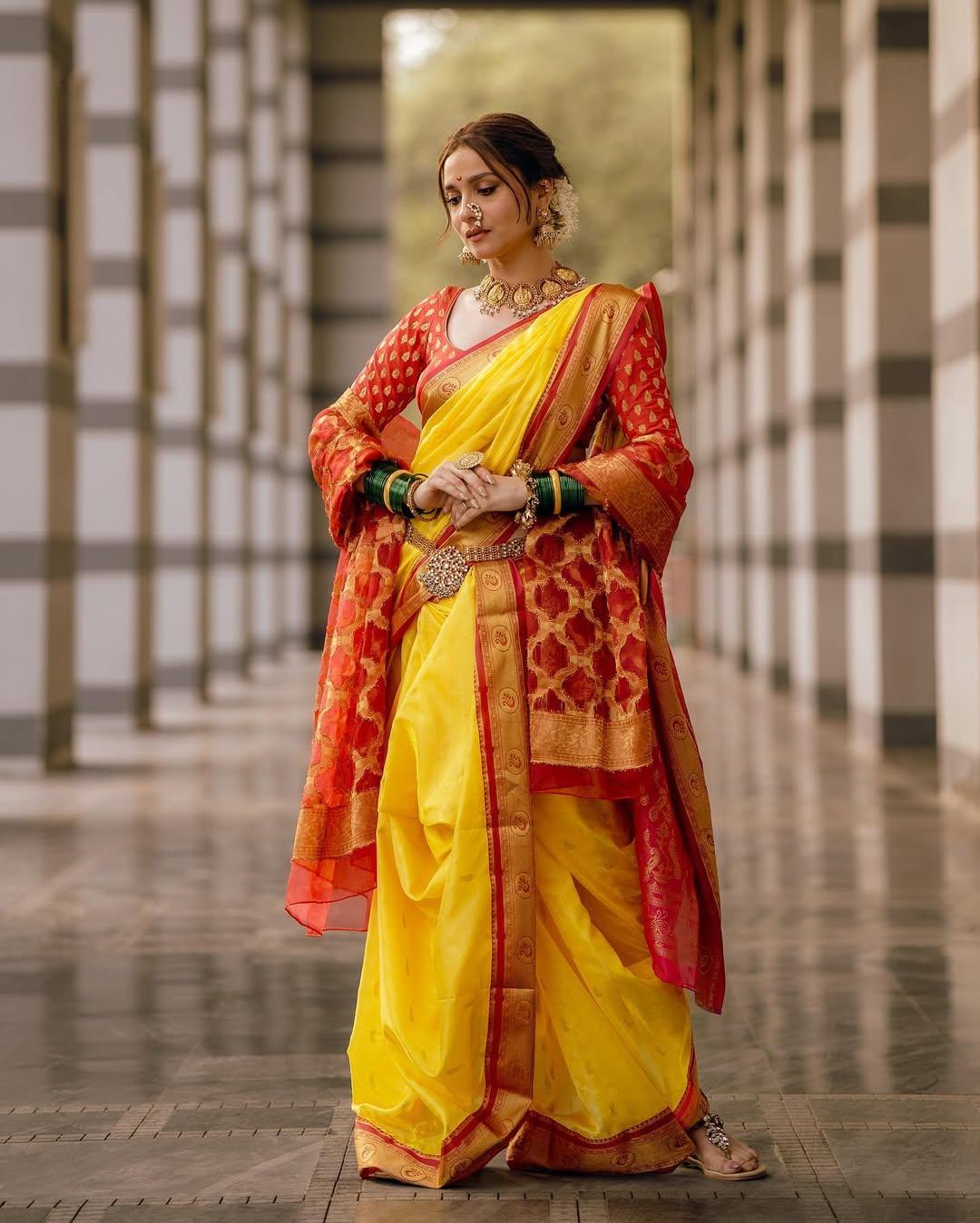 In this look, Ankita wore a beautiful yellow nauvari with a red border. The actress paired her saree with a contrasting red blouse featuring long sleeves and matched it with a coordinating shawl, giving off proper Marathi mulgi vibes