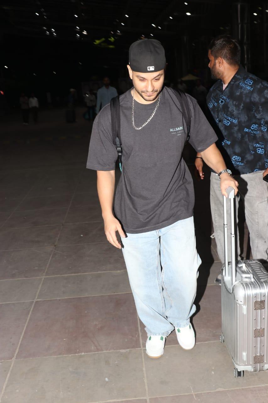 Kunal Khemu's casual airport look included a black T-shirt, loose light-colored pants, and a stylish chain