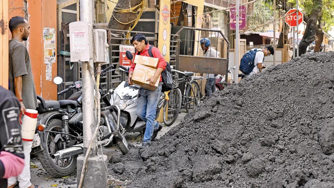 A man struggles with boxes on what is left of a footpath at V S Agashe Road in Dadar West. Pic/Ashish Raje