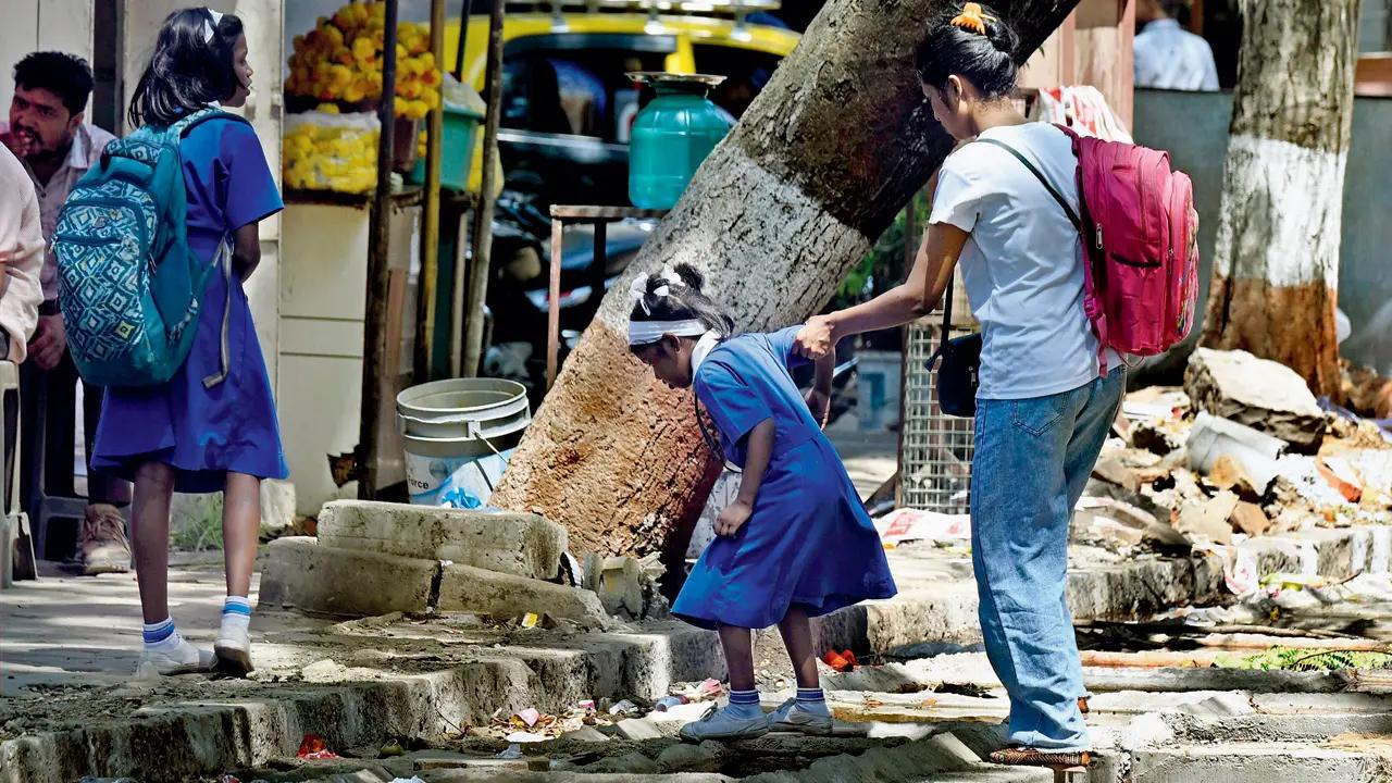 A woman helps her child navigate an risky patch of a road being concreted in Mahim West. Pic/Ashish Raje