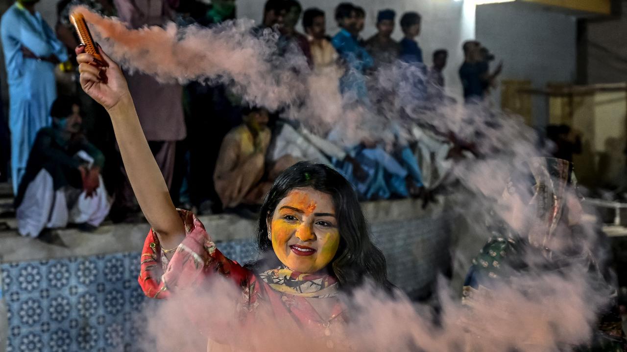 A woman diffuses coloured powder during the celebration of Holi, the Hindu spring festival of colours, in Karachi