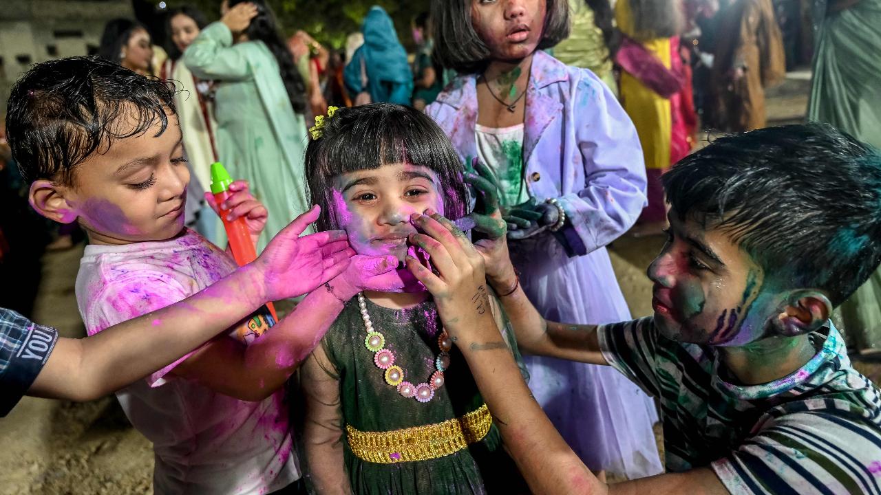 Children smear coloured powder on each other during the celebration of Holi, the Hindu spring festival of colours on the same night