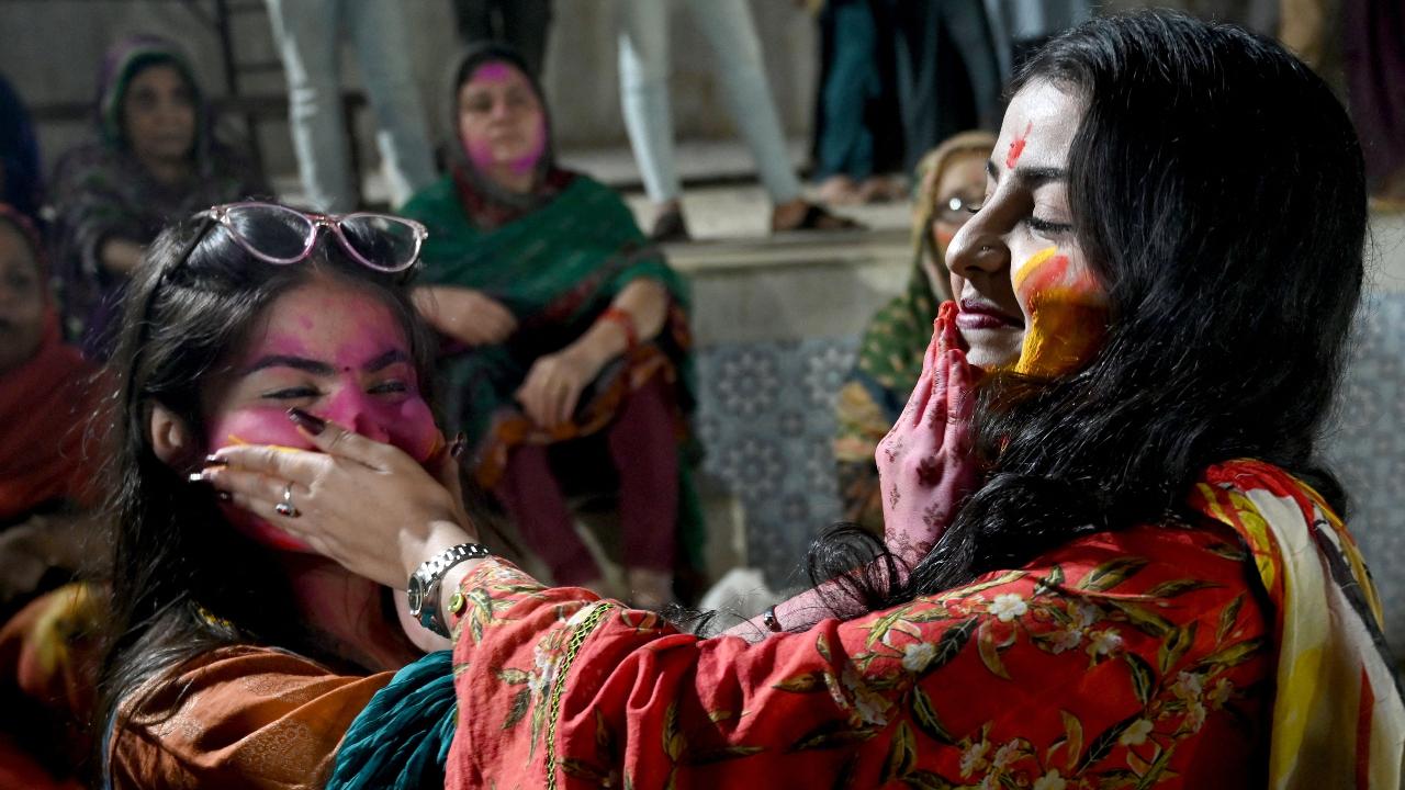 Women smear coloured powder on each other during the celebration of Holi, the Hindu spring festival of colours on March 13