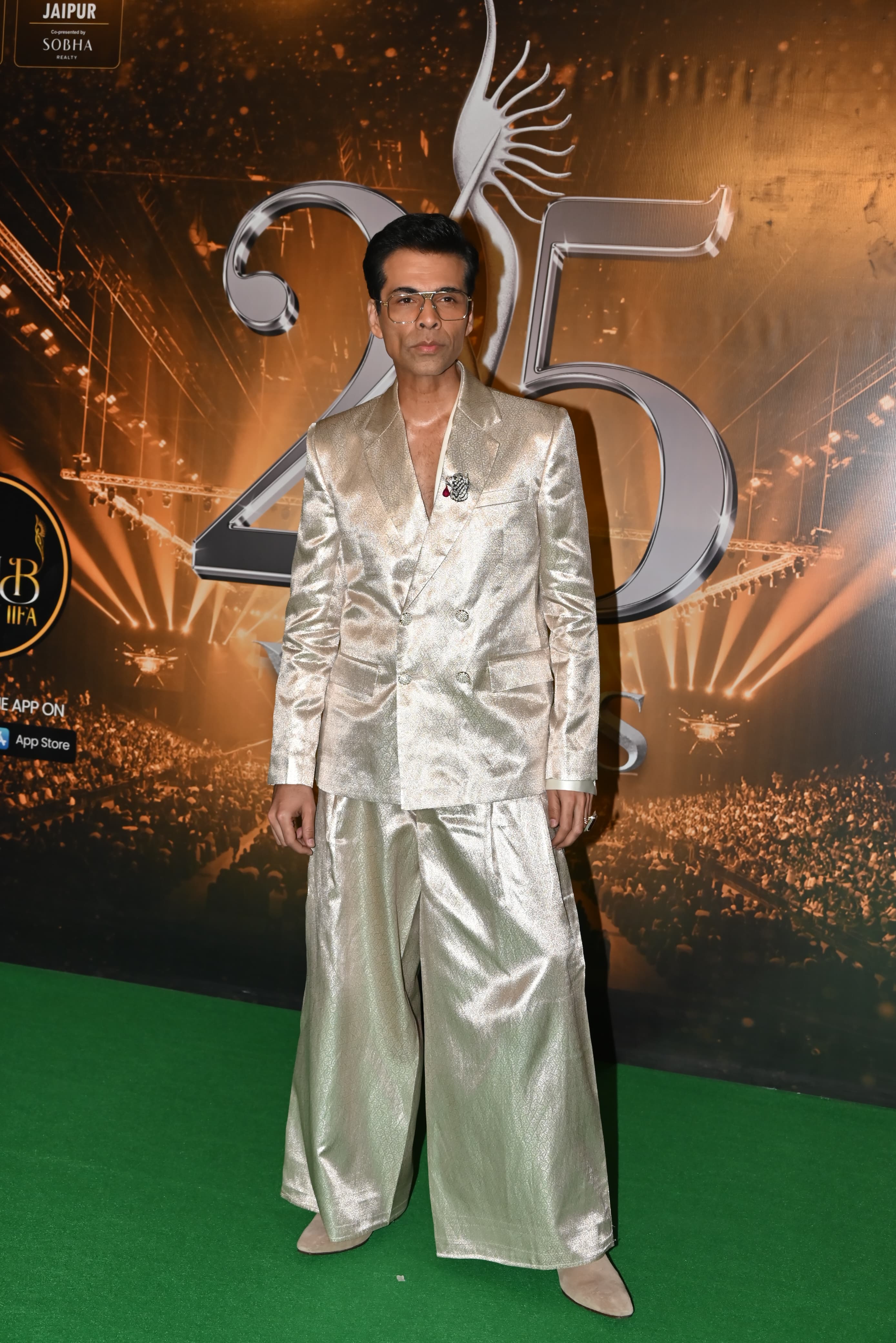 Karan Johar posed for the cameramen stationed in shiny silver pants paired with a matching blazer