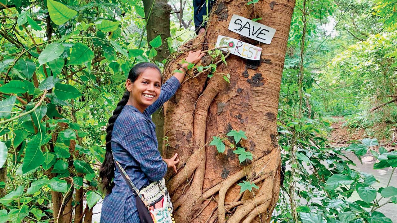 Manisha Dhinde places a sign that says Save Forest on a tree during a trail. PICS COURTESY/MANISHA DHINDE