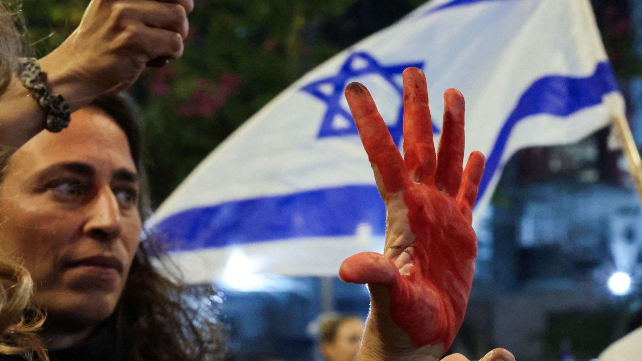 A woman is seen showing her palm coloured in red, representing the hostage's pain as they are held by Palestinian militants 