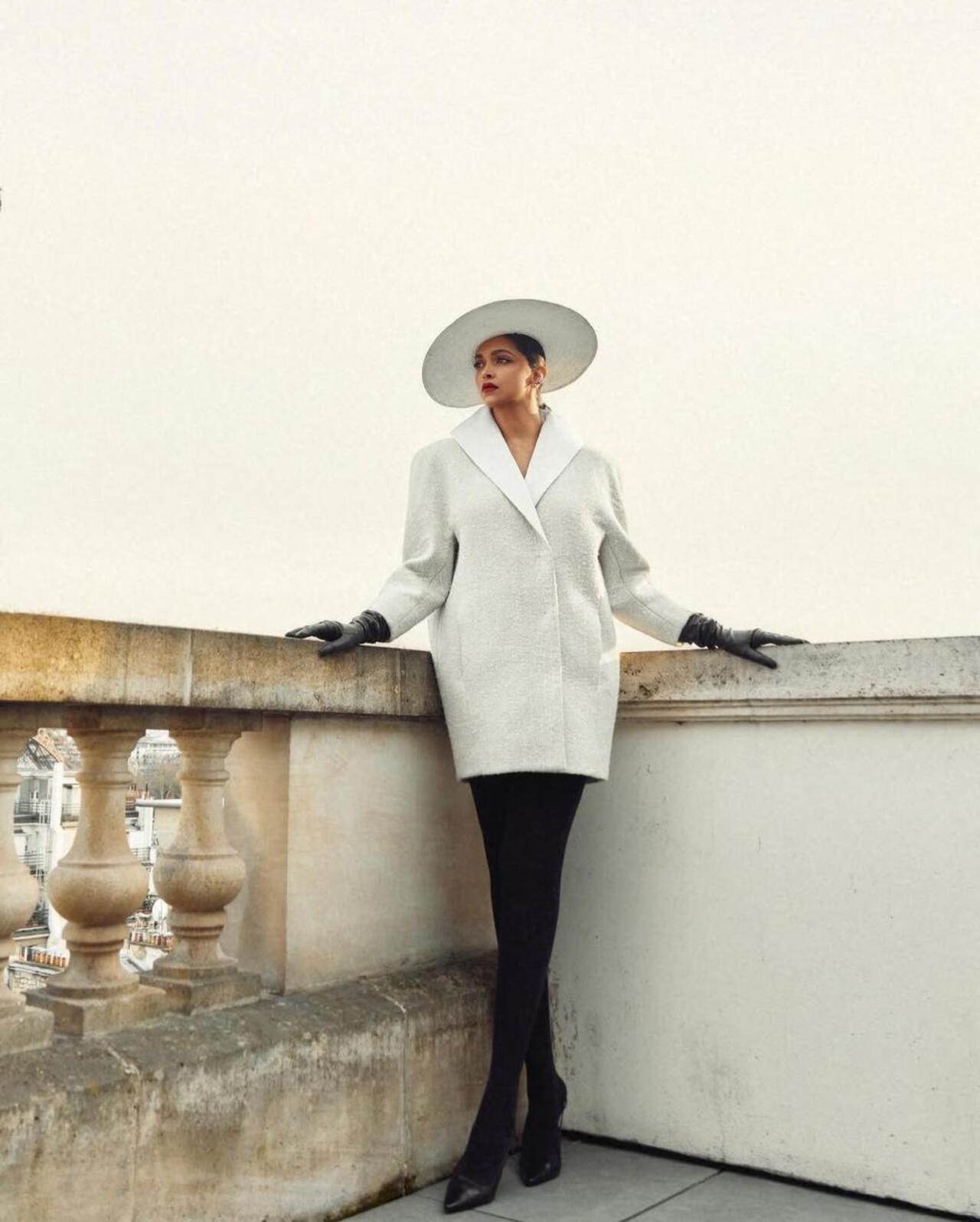 She donned a hat, scarf to tie up her hair and a dash of classic red lipstick with a white oversized coat and all back heels and gloves. 