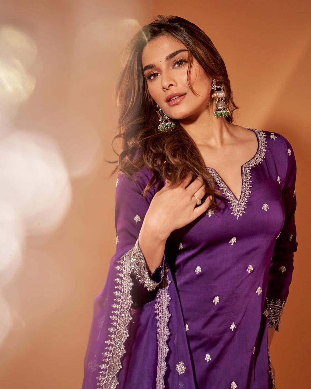 Saiee Manjrekar looks vibrant in a bright purple outfit, detailed with a silver border and intricate embellishments. She accessorizes with chunky oxidized earrings, making a glamorous fashion statement