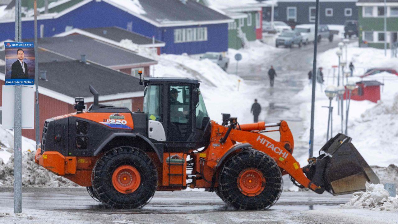 A snow-clearing dumper truck drives past a poster for the Greenlandic political party Demokraatit in Nuuk 