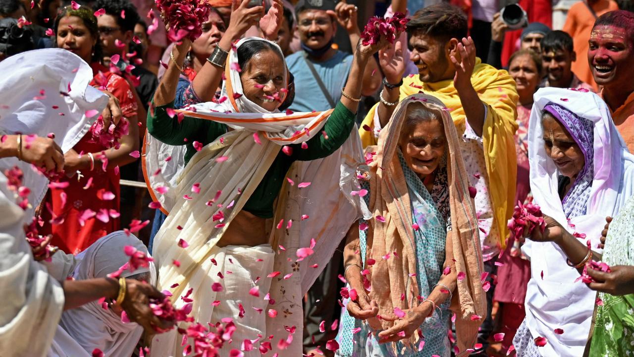 Widows shower flower petals as they dance and play with gulal at the temple 
