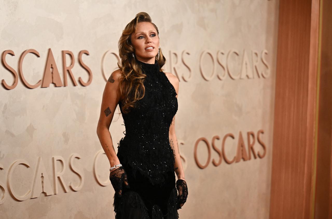 Miley Cyrus arrived in a head-turning outfit that's sure to be remembered. She wore a stunning black halter gown glittered with intricate embellishments. The dress was paired with lace gloves, adding a touch of old-school Hollywood glamour to her overall look.